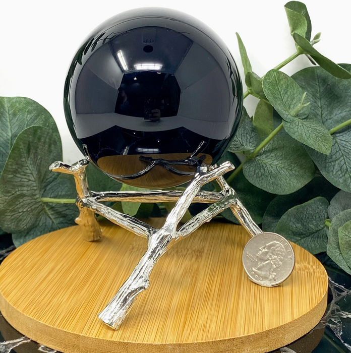 A large silver-plated metal stand for a crystal ball